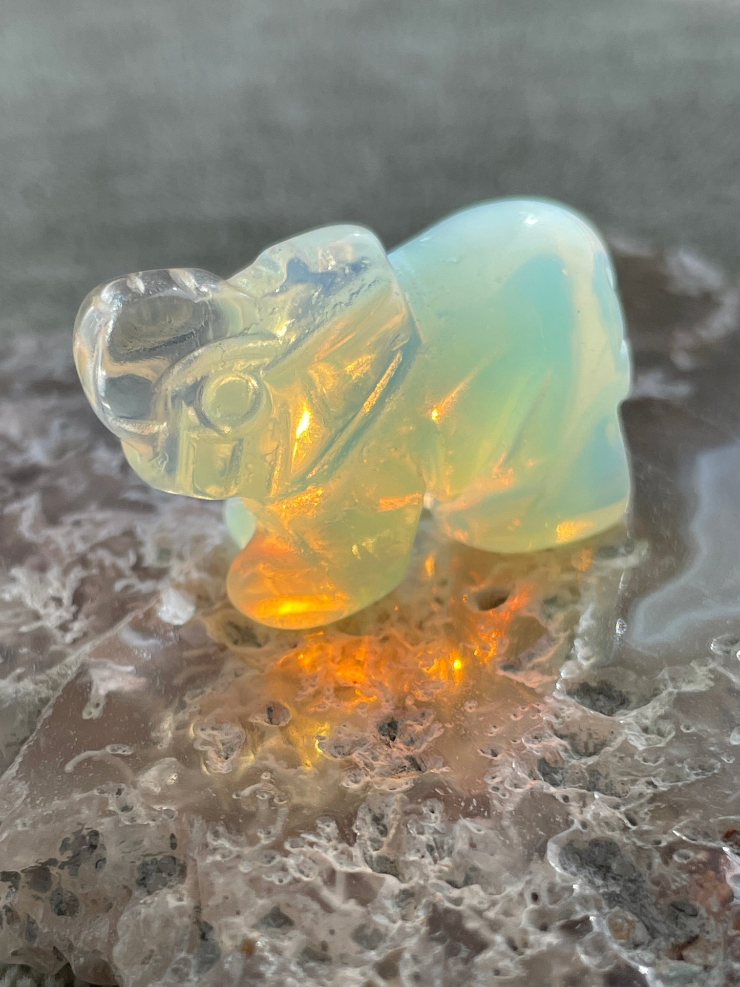 hand-carved opalite elephant figurine glowing with blue and gold hues, spiritual crystal animal totem