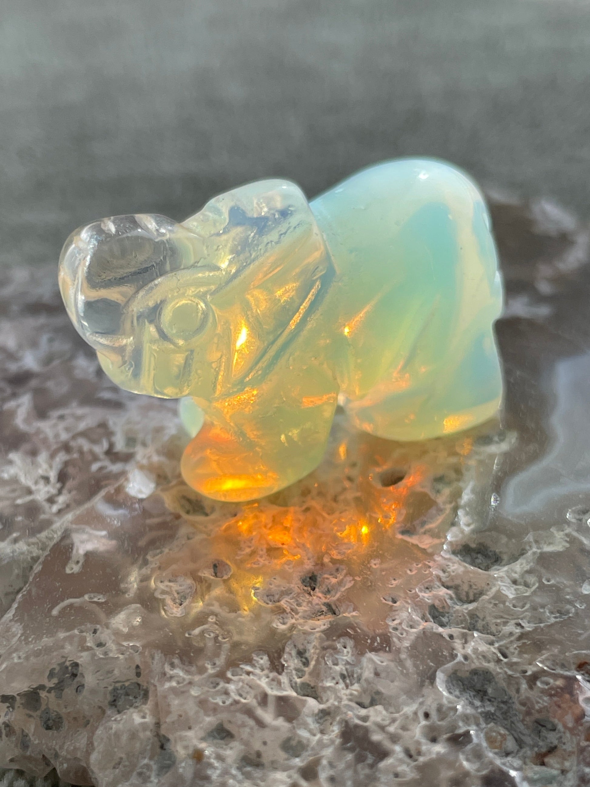 hand-carved opalite elephant figurine glowing with blue and gold hues, spiritual crystal animal totem