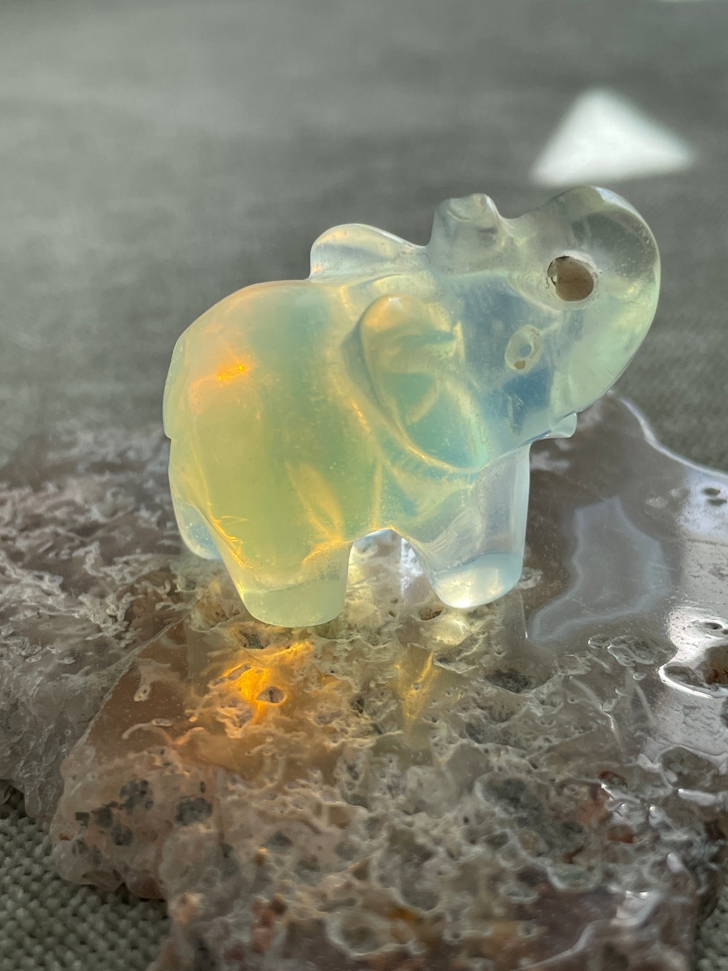 hand-carved opalite elephant figurine glowing with blue and gold hues, spiritual crystal animal totem